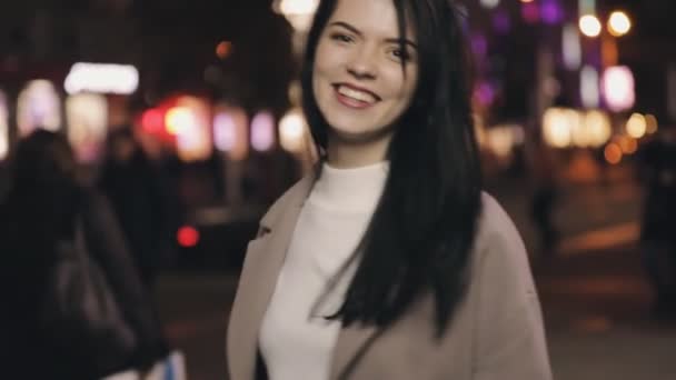 Привлекательная женщина кокетка позирует перед камерой в ночном городе, замедленная съемка — стоковое видео