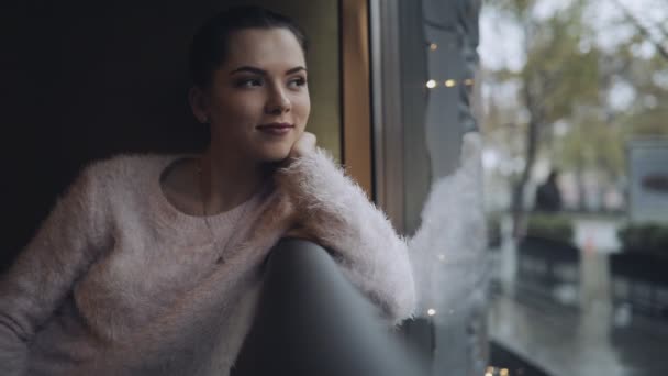 Femme mignonne assise à la fenêtre dans un café — Video