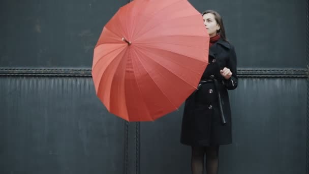 Αργή κίνηση γυναίκα κάτω από την κόκκινη ομπρέλα κοντά σε γκρι φράχτη — Αρχείο Βίντεο