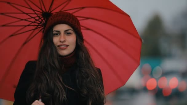 Mujer sonriente girando paraguas rojo en la ciudad de la noche — Vídeo de stock