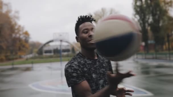 Man rotating ball on finger in basketball court — Stock Video