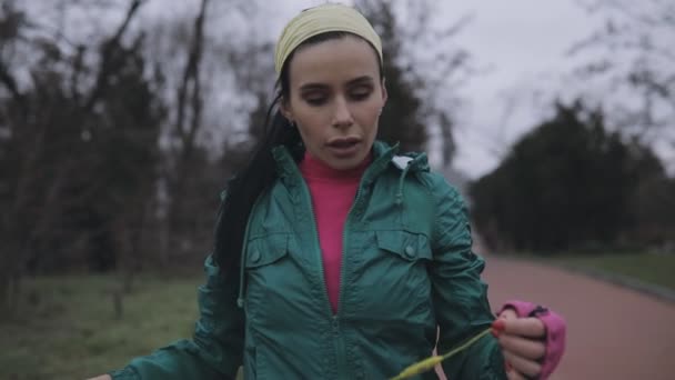 Жінка з'єднує бездротові навушники і працює на відкритому повітрі в холодний день — стокове відео