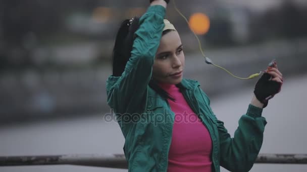 Jogger γυναίκα φορούν κουκούλα και ασύρματα ακουστικά σε κρύα ημέρα του χειμώνα — Αρχείο Βίντεο