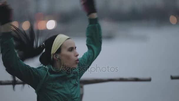 Спортсменка прыгает и греется в холодном зимнем городе — стоковое видео