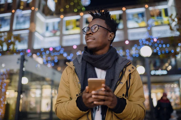 Afrikai ember használ smartphone-éjszakai állandó a sötét város: — Stock Fotó