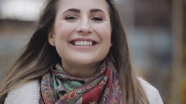 Esmer saçlı bir şehirde gülümseyen genç kadın portresi