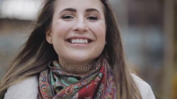 Portret van een jonge vrouw met brunette haar lachend in een stad — Stockvideo