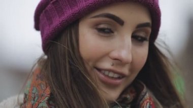 Mor şapka ve şık bir görünüm bir şehirde gülümseyen genç kadın