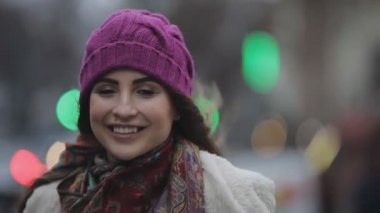 Bir şehirde esmer saçlı genç gülümseyen kadın portresi