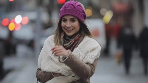 Mujer joven con sombrero violeta caminando en una ciudad — Vídeo de stock