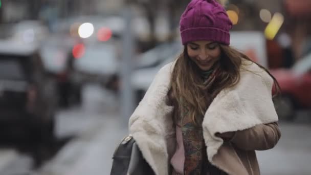 Young woman in violet hat walking in a city — Stock Video