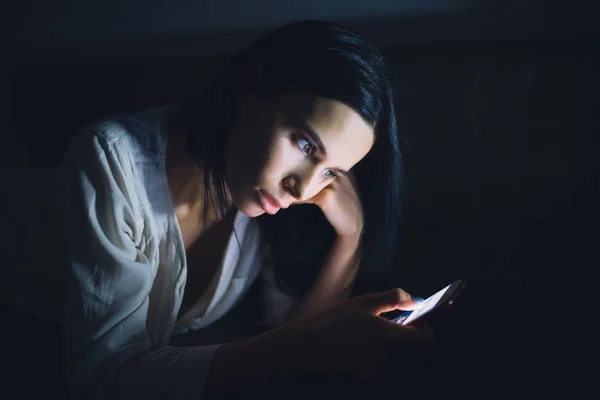 Женщина, использующая синий экран смартфона ночью перед сном — стоковое фото