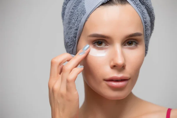 Beauty, woman apply moisturizing cream on skin under eye