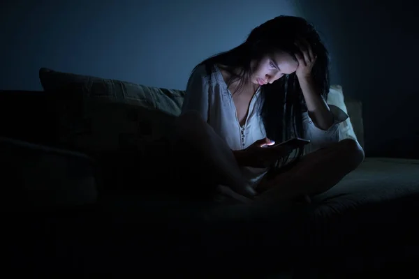 Donna stanca utilizzando lo schermo blu dello smartphone di notte camera oscura — Foto Stock