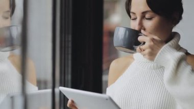 Sevimli kadın Tablet Pc bir kafede çay içme pencere kullanma