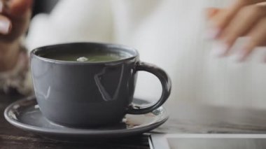 Tablet Pc, bir tabloda çay kullanan kadın görüntüsünü kırpılmış