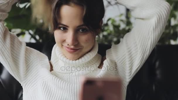 Mujer corrige el peinado mirando en el teléfono inteligente como espejo — Vídeos de Stock