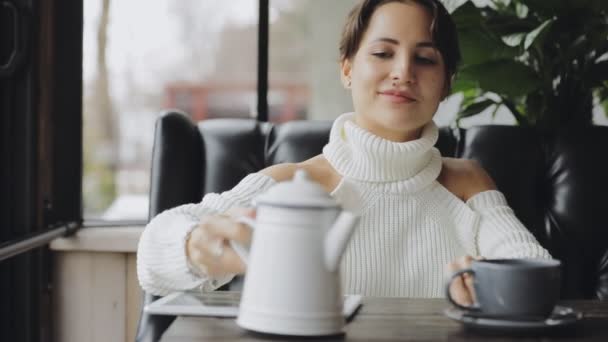 逗人喜爱的妇女倾吐的茶入杯子在咖啡馆 — 图库视频影像