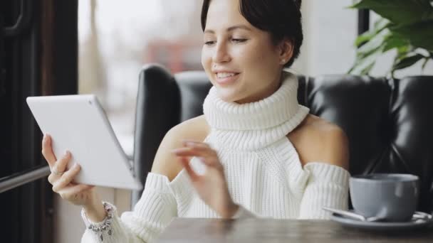 Mooie vrouw met behulp van de tablet Pc in een café thee drinken lachend — Stockvideo