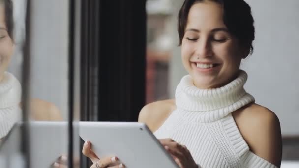 Ładna kobieta za pomocą tabletu w kawiarni w pobliżu okna — Wideo stockowe