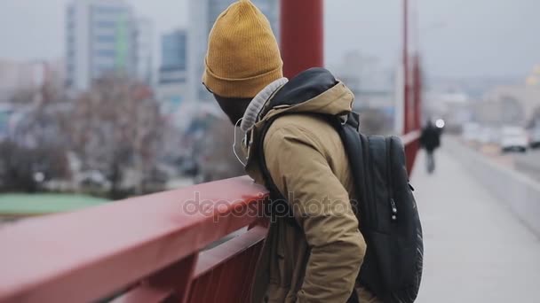 Joven negro con gorra pensando en un puente — Vídeo de stock