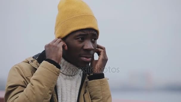 Jovem negro sozinho ouvir música em fones de ouvido e pensar de pé na ponte — Vídeo de Stock