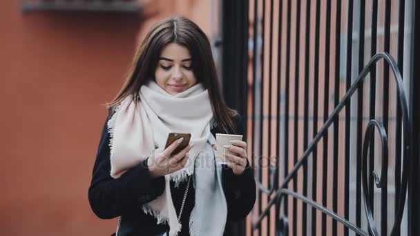 Mulher andando perto de cerca usar smartphone e beber café — Vídeo de Stock