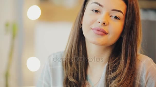 Портрет молодой женщины, смотрящей на камеру в кафе — стоковое видео