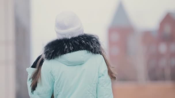 Arka görünümü kadında kış şapka ve şehirde yürüyüş ceket — Stok video