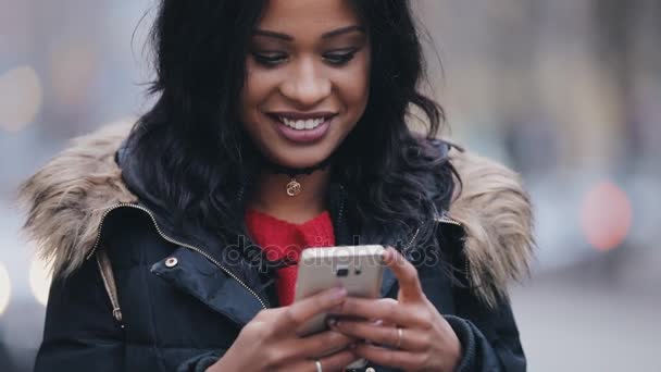 Mujer joven de pie en la calle en la mensajería de invierno en el teléfono inteligente — Vídeos de Stock