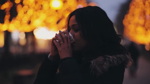 Hermosa mujer multirracial bebiendo té en la ciudad de noche — Vídeos de Stock