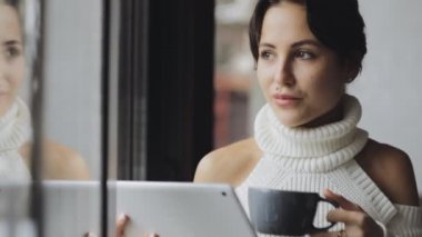 Sevimli kadın Tablet Pc bir kafede çay içme pencere kullanma