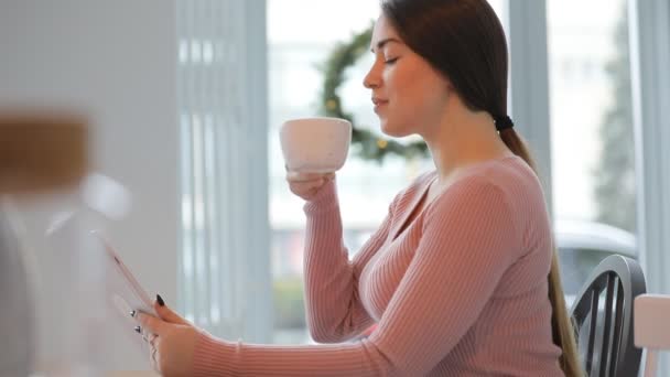タブレットを使用している間、カフェでコーヒーを飲む若い女性 — ストック動画