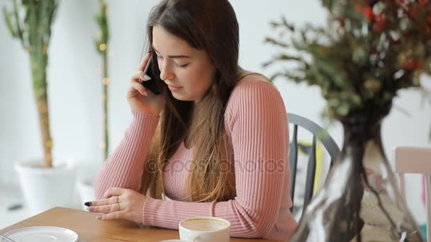 Vrouw praten door smartphone in witte café — Stockvideo