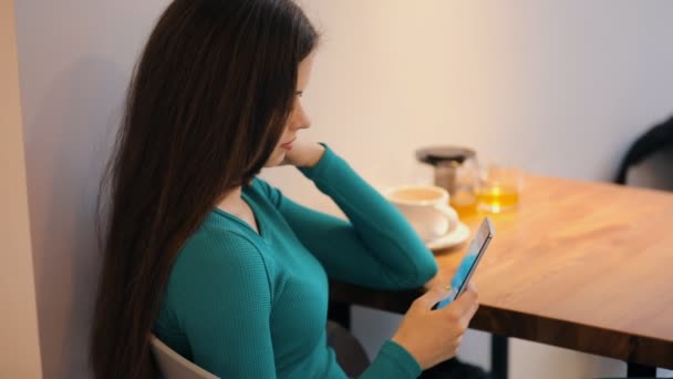 Женщина с помощью смартфона сидит и отдыхает в кафе — стоковое видео