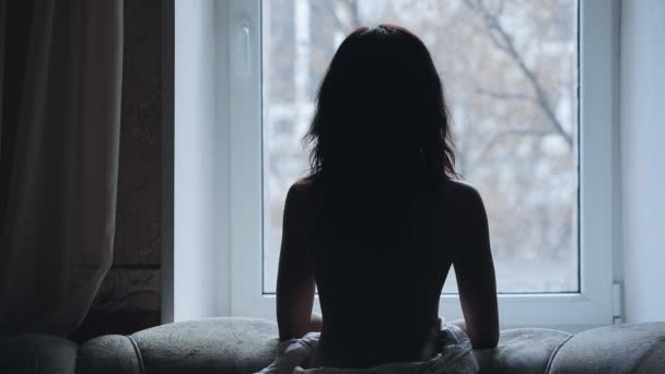 Σιλουέτα του γυμνή γυναίκα ψάχνει μέσα από το παράθυρο στο σπίτι — Αρχείο Βίντεο