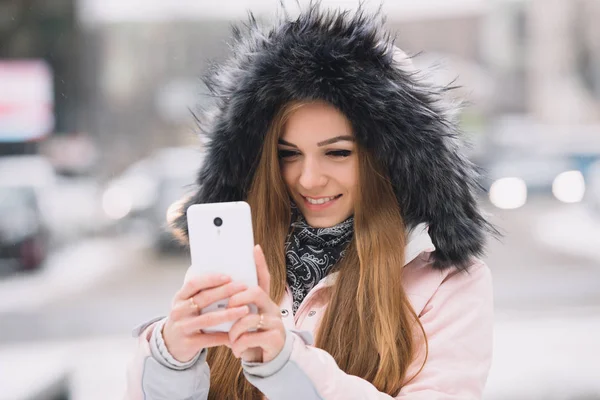 Молодая женщина делает мобильное фото в зимний снежный город, технологии смартфонов — стоковое фото