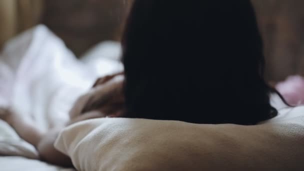 Vrouw wordt wakker in de ochtend liggend op bed, achteraanzicht — Stockvideo