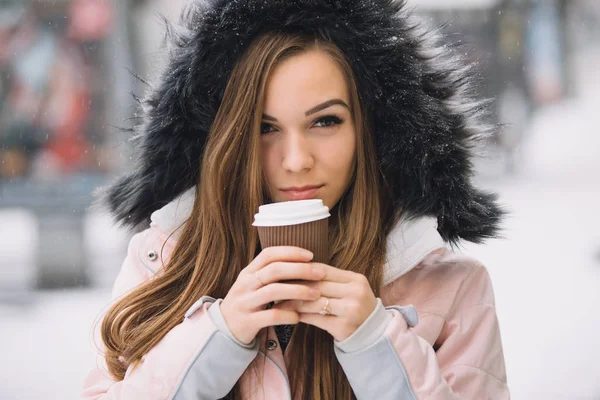 Mooie jonge vrouw houden van papier koffie kopje op winter stedelijke stad — Stockfoto