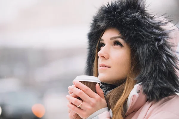 สาวสวยถือถ้วยกาแฟกระดาษในเมืองเมืองฤดูหนาว — ภาพถ่ายสต็อก