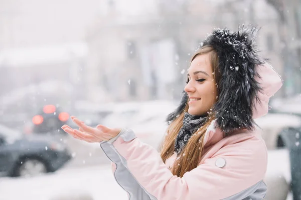 Gelukkig meisje vangsten sneeuwvlokken met zijn handen, genieten van de wintervakantie — Stockfoto