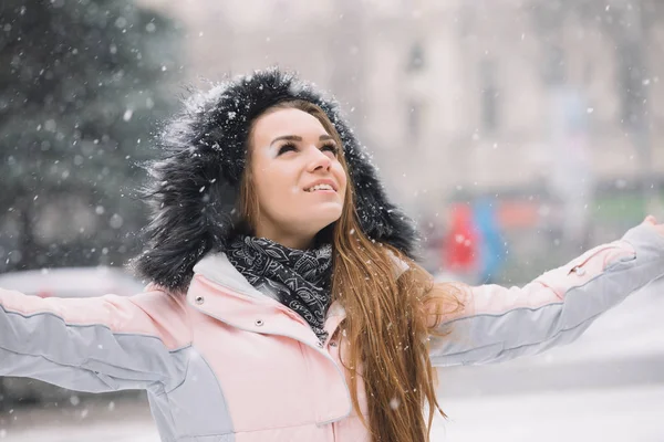 Gelukkig jonge vrouw met opgeheven handen genieten van winterse besneeuwde dag — Stockfoto