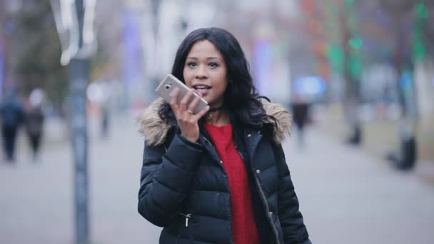 Mujer caminando en la calle hablando de un mensaje de voz en el teléfono inteligente — Vídeos de Stock