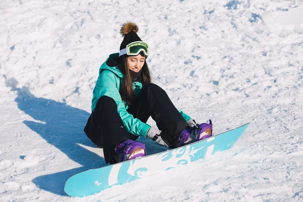 Ocio, invierno, concepto deportivo - snowboarder mujer sentada y sujetar el tablero en las piernas —  Fotos de Stock