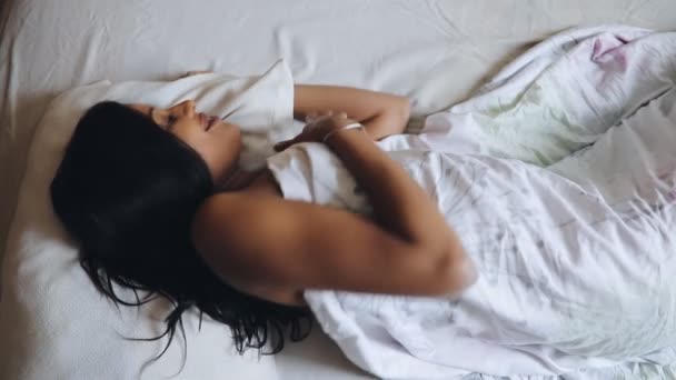 Vrouw wordt wakker in de ochtend liggend op bed, bovenaanzicht — Stockvideo