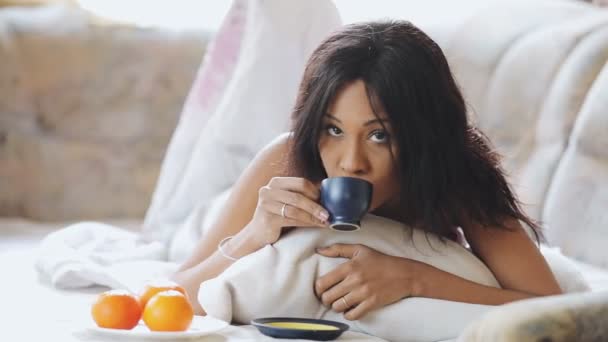 家でお茶を飲むの居心地の良いベッドでブルネットの女性 — ストック動画