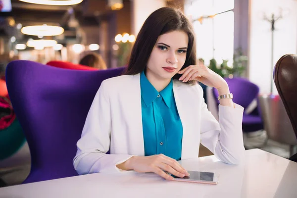 Strict business woman sitting at table in a futuristic cafe — Stock Photo, Image