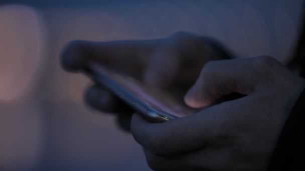 Personas no identificadas manos sosteniendo teléfono inteligente móvil en la ciudad nocturna — Vídeos de Stock