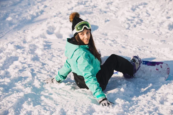 Sorridente ragazza snowboarder sedersi su una neve — Foto Stock