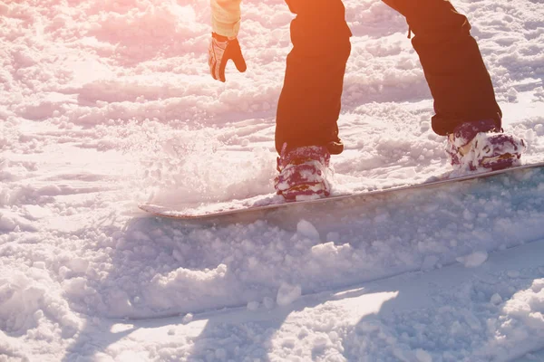 Las piernas del snowboarder que monta en una nieve con el resplandor del sol —  Fotos de Stock